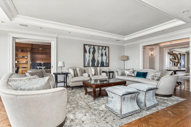 living area featuring a tray ceiling, visible vents, and crown molding