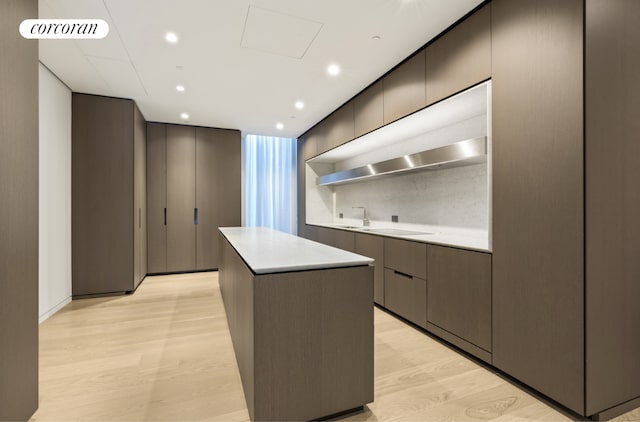 kitchen with sink, light hardwood / wood-style flooring, a center island, tasteful backsplash, and black electric stovetop