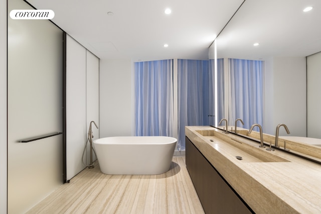 bathroom featuring vanity, wood-type flooring, and a tub to relax in