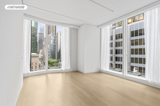 empty room with expansive windows, hardwood / wood-style flooring, and a wealth of natural light