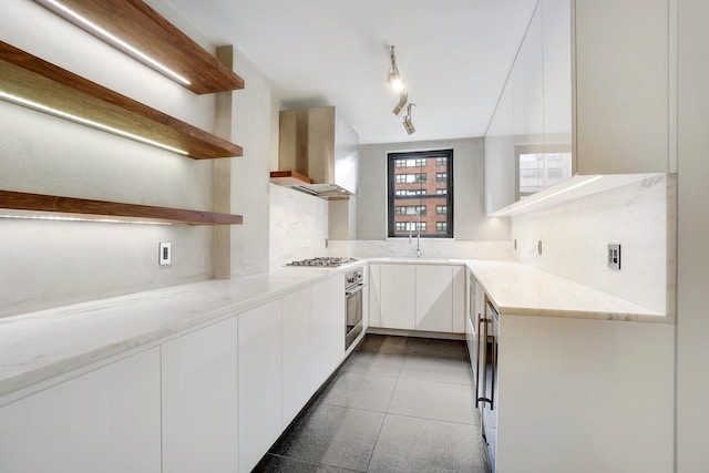 177 E 77th St Unit 5A, New York City, NY 10075 - kitchen with open shelves, wall chimney exhaust hood, stainless steel appliances, modern cabinets, and white cabinetry