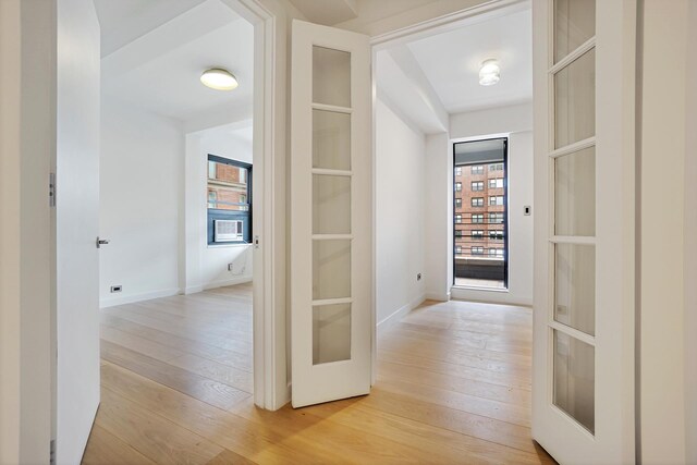 empty room featuring beamed ceiling, built in features, and light wood-type flooring