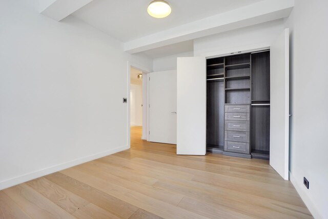 spare room featuring beam ceiling and light hardwood / wood-style floors