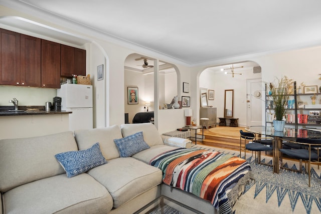 living area with arched walkways, a ceiling fan, and crown molding