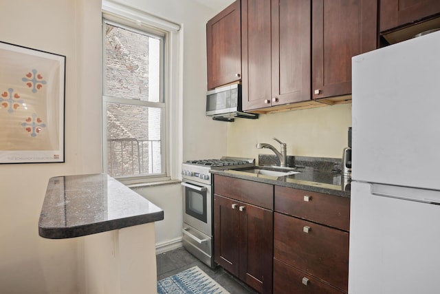 kitchen with stainless steel appliances, dark stone counters, and a sink