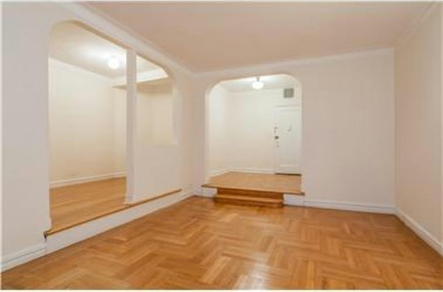 empty room featuring arched walkways and baseboards