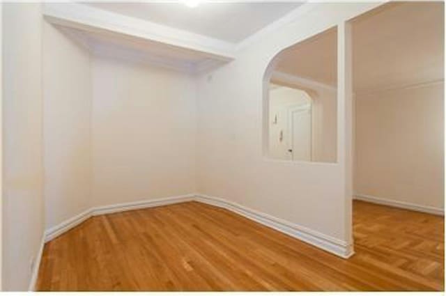 unfurnished room featuring baseboards, wood finished floors, and ornamental molding