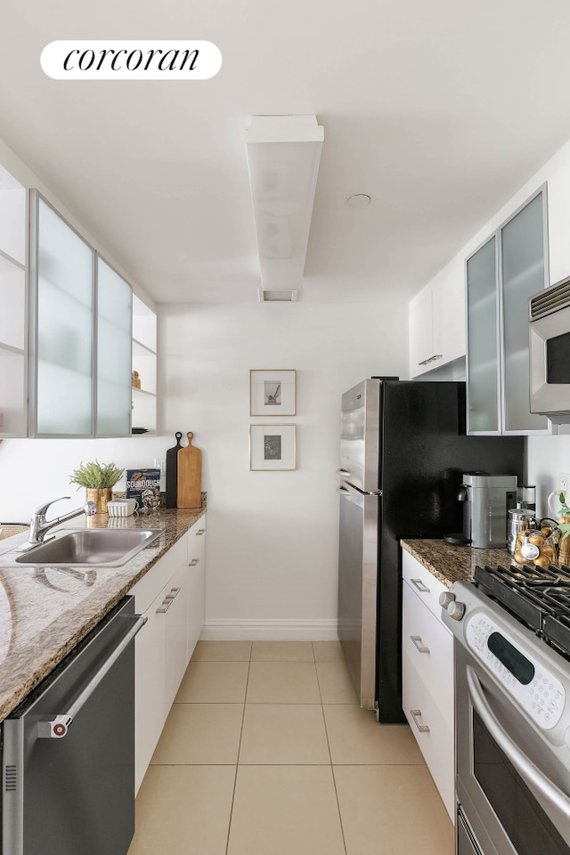 kitchen featuring stainless steel appliances, a sink, glass insert cabinets, and white cabinets