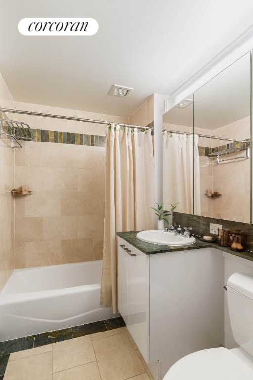 full bathroom featuring toilet, vanity, tile patterned flooring, and shower / tub combo with curtain