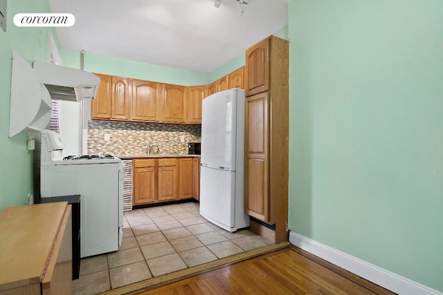 kitchen with sink, white appliances, tasteful backsplash, ventilation hood, and light hardwood / wood-style floors