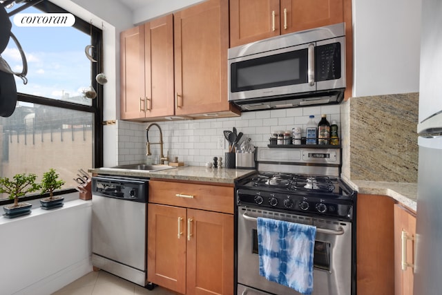 kitchen featuring light stone countertops, stainless steel appliances, decorative backsplash, sink, and light tile patterned floors