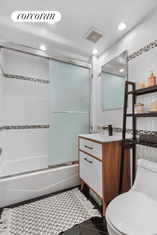 full bathroom with toilet, bath / shower combo with glass door, tile patterned flooring, and vanity