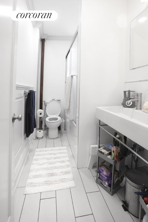 bathroom featuring shower / bath combination with glass door and toilet