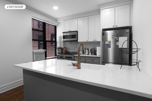 kitchen featuring white cabinetry, appliances with stainless steel finishes, backsplash, and kitchen peninsula