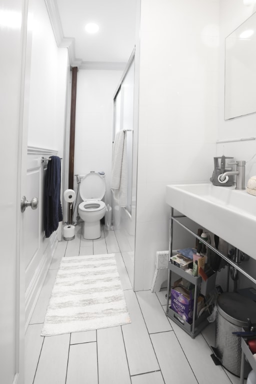 bathroom with crown molding, toilet, and combined bath / shower with glass door