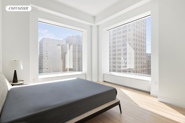 bedroom with light wood finished floors, a city view, and visible vents