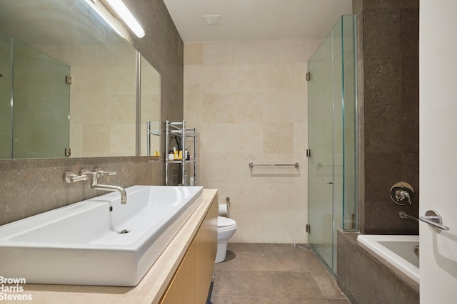 full bathroom with tile walls, vanity, independent shower and bath, and toilet