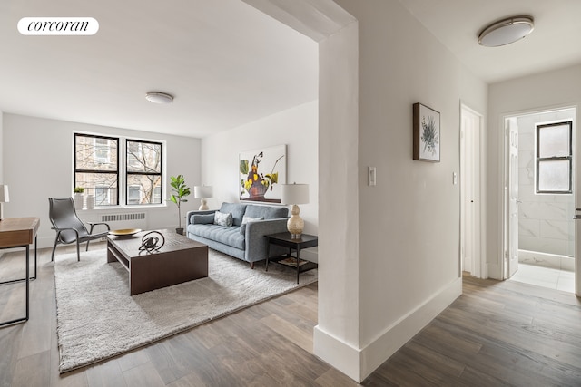 living room featuring radiator, baseboards, visible vents, and wood finished floors