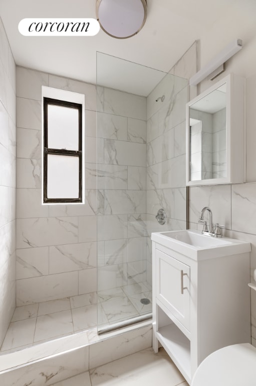 bathroom with vanity, tiled shower, tile walls, and toilet