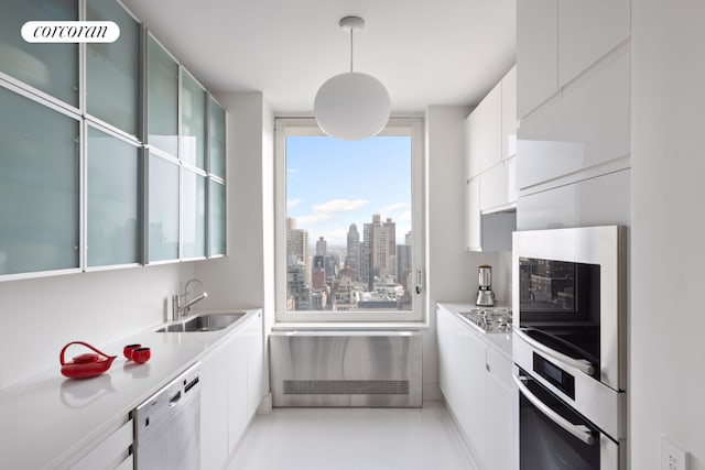 kitchen with white cabinetry, hanging light fixtures, stainless steel appliances, and sink