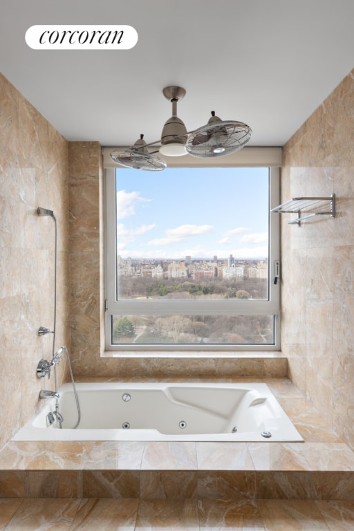 bathroom with a relaxing tiled tub and a healthy amount of sunlight