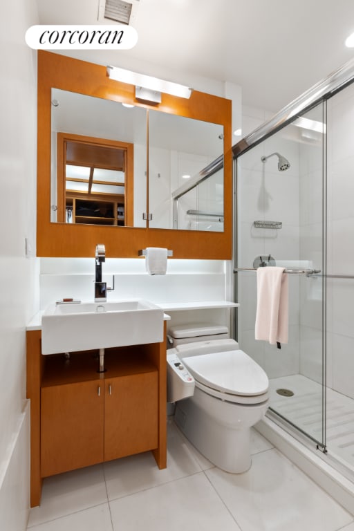 bathroom with vanity, tile patterned flooring, a shower with shower door, and toilet