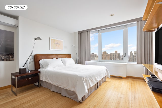 bedroom featuring a wall unit AC and light wood-type flooring