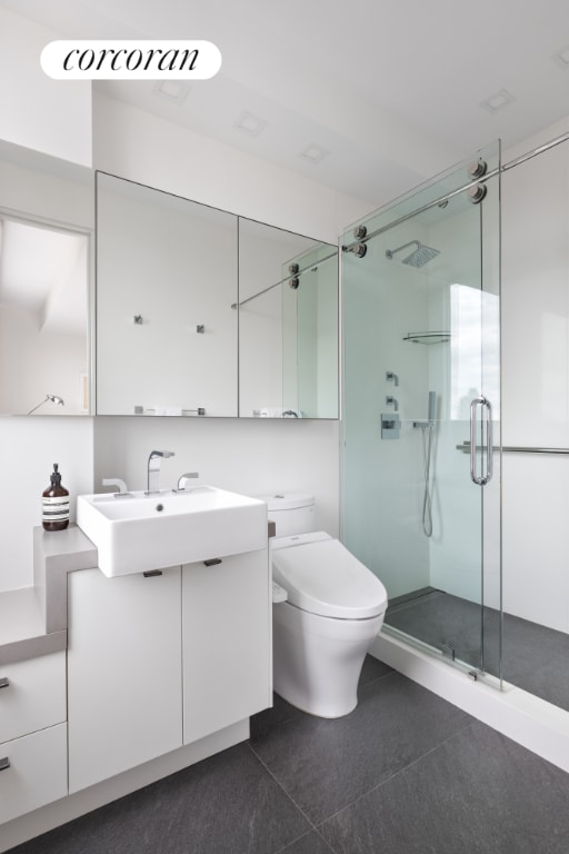 bathroom featuring vanity, tile patterned flooring, toilet, and walk in shower