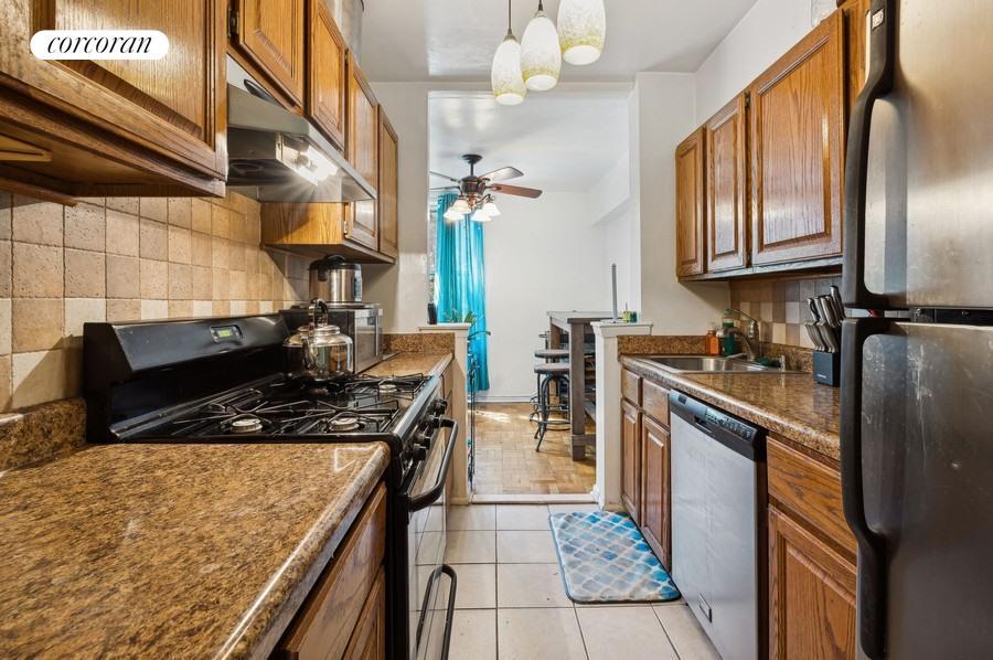 kitchen with light tile patterned flooring, sink, pendant lighting, ceiling fan, and stainless steel appliances