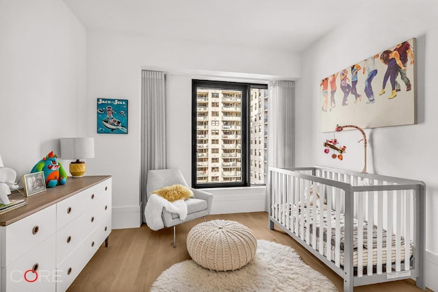 bedroom with a nursery area and light hardwood / wood-style floors