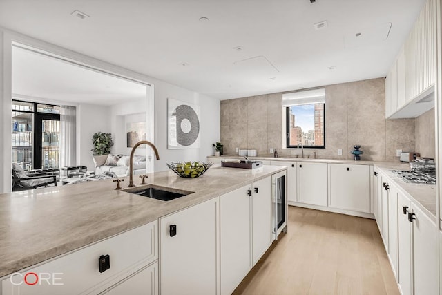 kitchen featuring white cabinetry, sink, stainless steel gas stovetop, and light wood-type flooring