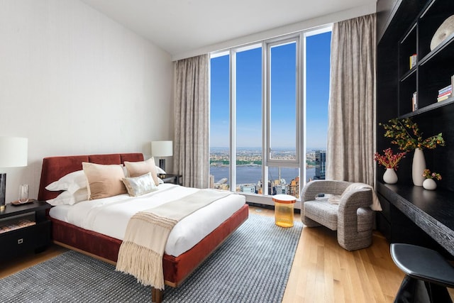 bedroom featuring a water view, wood-type flooring, and floor to ceiling windows