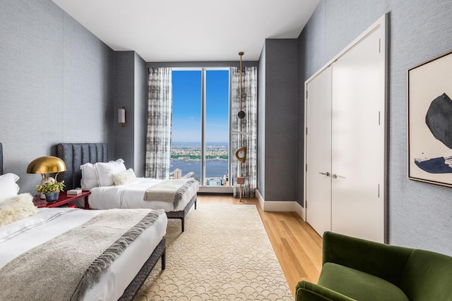 bedroom featuring a water view and light wood-type flooring