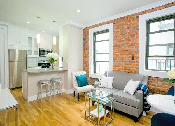 living area with a wealth of natural light, light wood finished floors, and brick wall