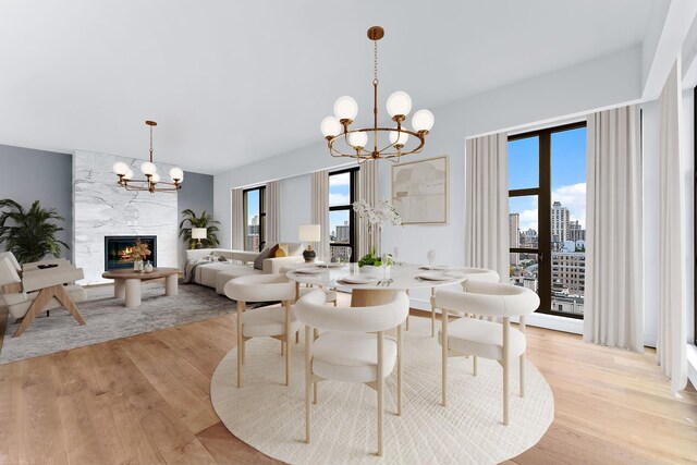 dining space featuring light wood-type flooring, a fireplace, and an inviting chandelier