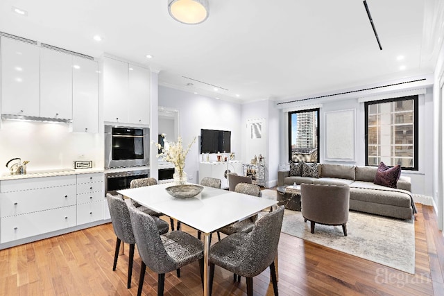 dining space with crown molding and light hardwood / wood-style flooring