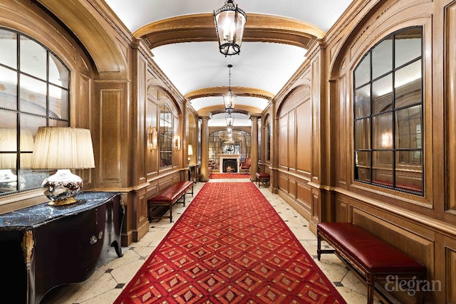 hallway featuring decorative columns, lofted ceiling, and a notable chandelier