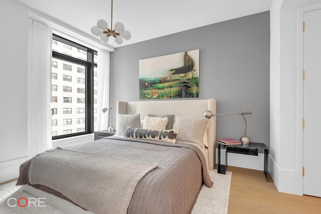 bedroom featuring an inviting chandelier and light hardwood / wood-style flooring