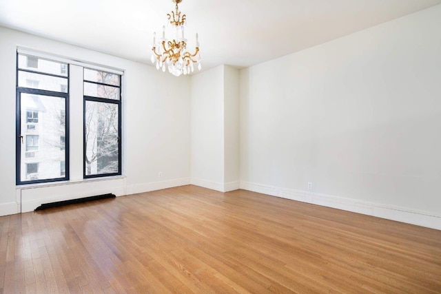 unfurnished room featuring a notable chandelier and light hardwood / wood-style floors