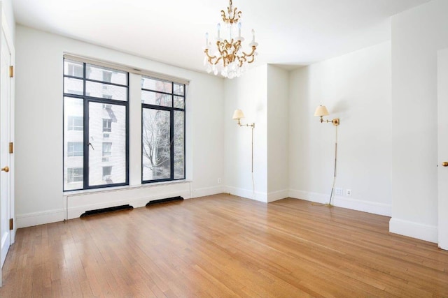 spare room with hardwood / wood-style floors and a notable chandelier