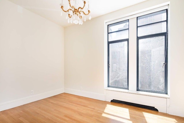 spare room with hardwood / wood-style floors and a chandelier