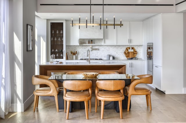 kitchen with a sink, tasteful backsplash, light countertops, and white cabinetry