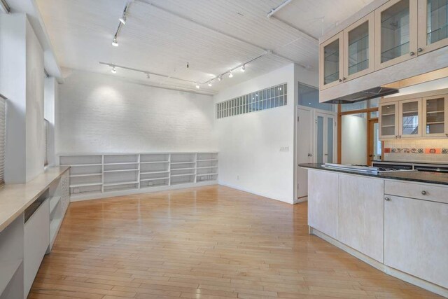 kitchen featuring rail lighting, light wood-type flooring, stainless steel gas cooktop, and a high ceiling