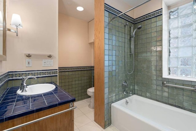 full bathroom featuring toilet, tile walls, vanity, tiled shower / bath combo, and tile patterned flooring