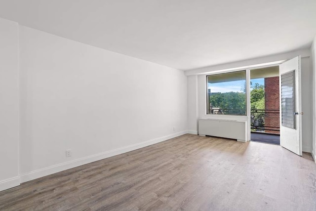 spare room with radiator heating unit and wood-type flooring