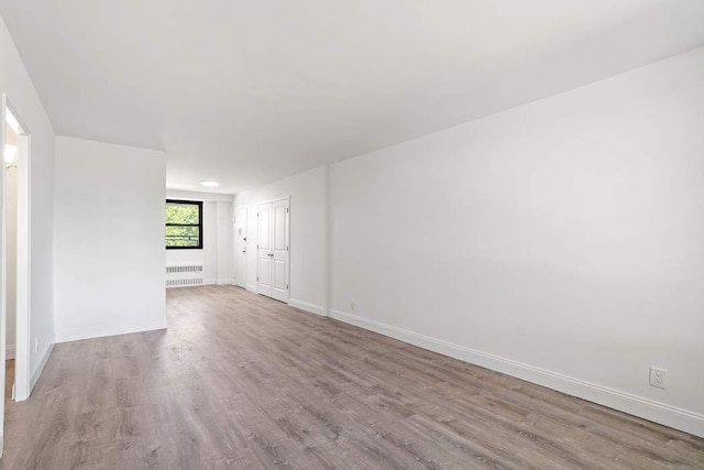 unfurnished room with radiator and light hardwood / wood-style flooring