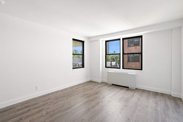 spare room featuring radiator and light hardwood / wood-style flooring