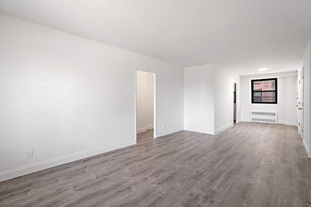 unfurnished room featuring radiator heating unit and light hardwood / wood-style floors