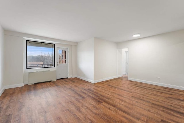 empty room with dark hardwood / wood-style flooring and radiator