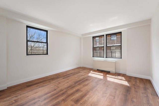 spare room with radiator heating unit and wood-type flooring